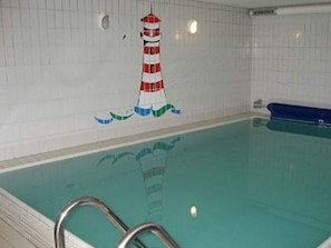 Ein Swimmingpool mit einer Fliesenwand, die ein Leuchtturm-Mural zeigt.