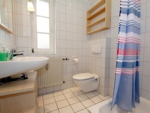 A bathroom with a white sink, toilet, and shower curtain. - Badestrasse 40a - Holiday Apartment 1 (Wyk auf Foehr)