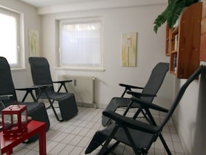 Ein Zimmer mit drei schwarzen Stühlen, einem roten Tisch und einem Heizkörper.
