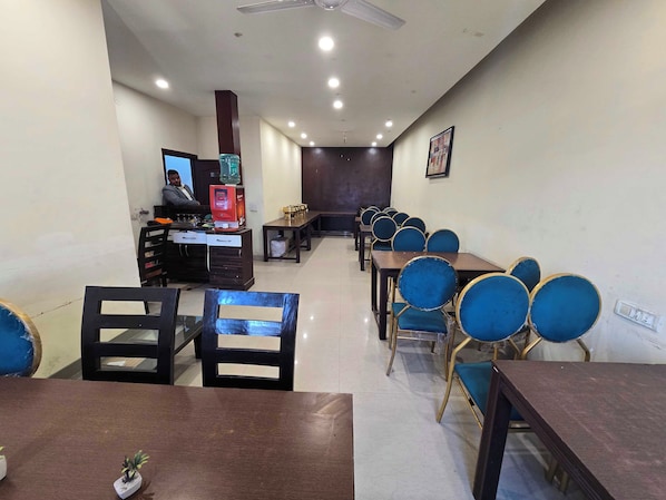 A conference room with multiple tables and chairs, a coffee machine, and a counter with a computer. - Hotel O shingari royale (Amritsar)