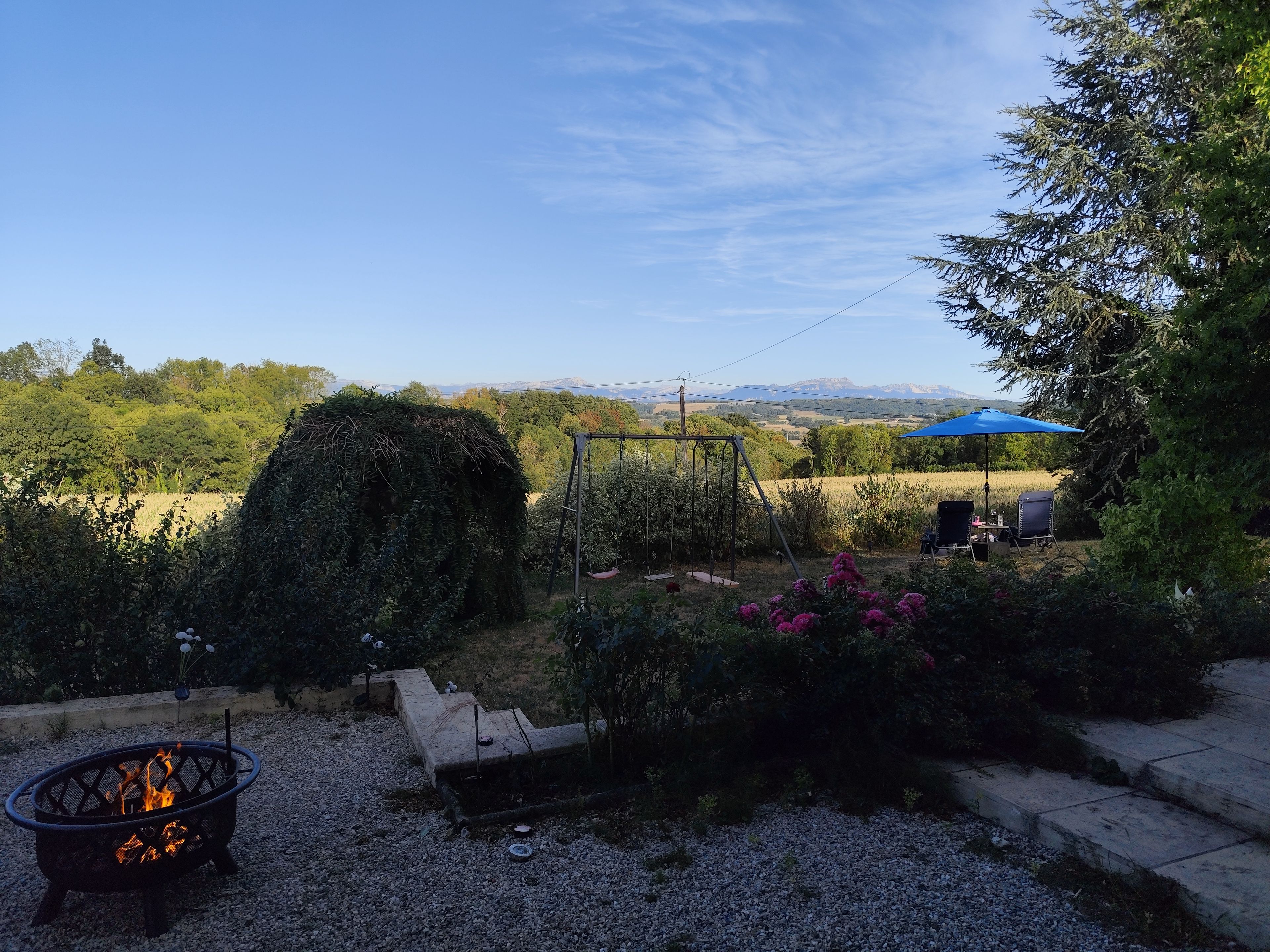 Ein Garten mit Feuerstelle, Schaukel und Blick auf ferne Berge.