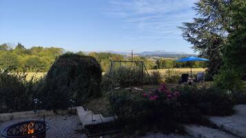 Ein Garten mit Feuerstelle, Schaukel und Blick auf ferne Berge.