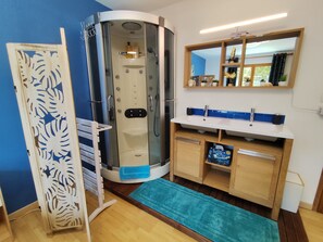 Une salle de bain avec une douche, un lavabo et un miroir.
