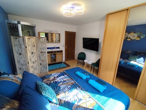 A bedroom with a bed, a desk, a TV, and a wardrobe.