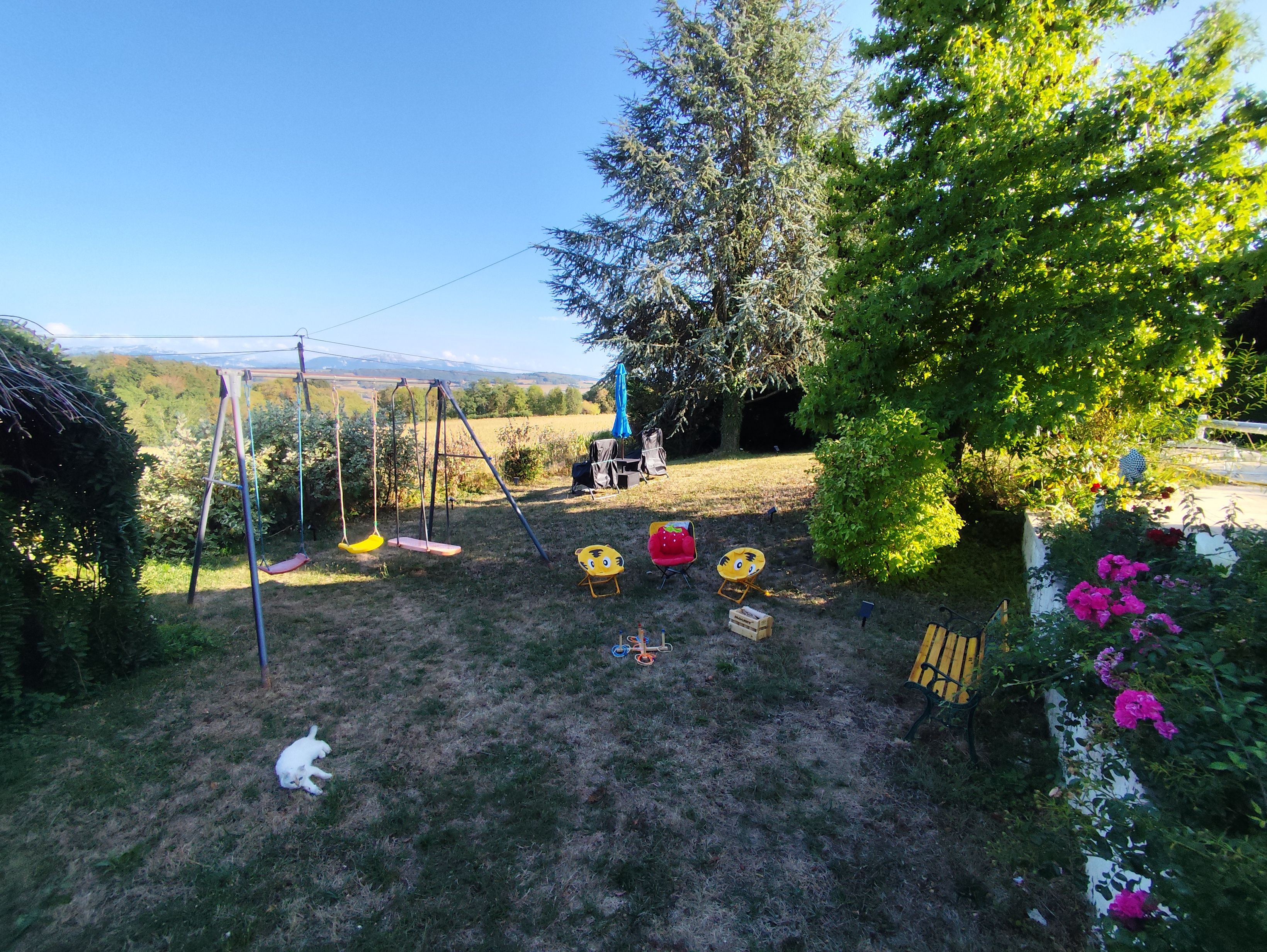 A backyard with a swing set, a small table, and a chair.
