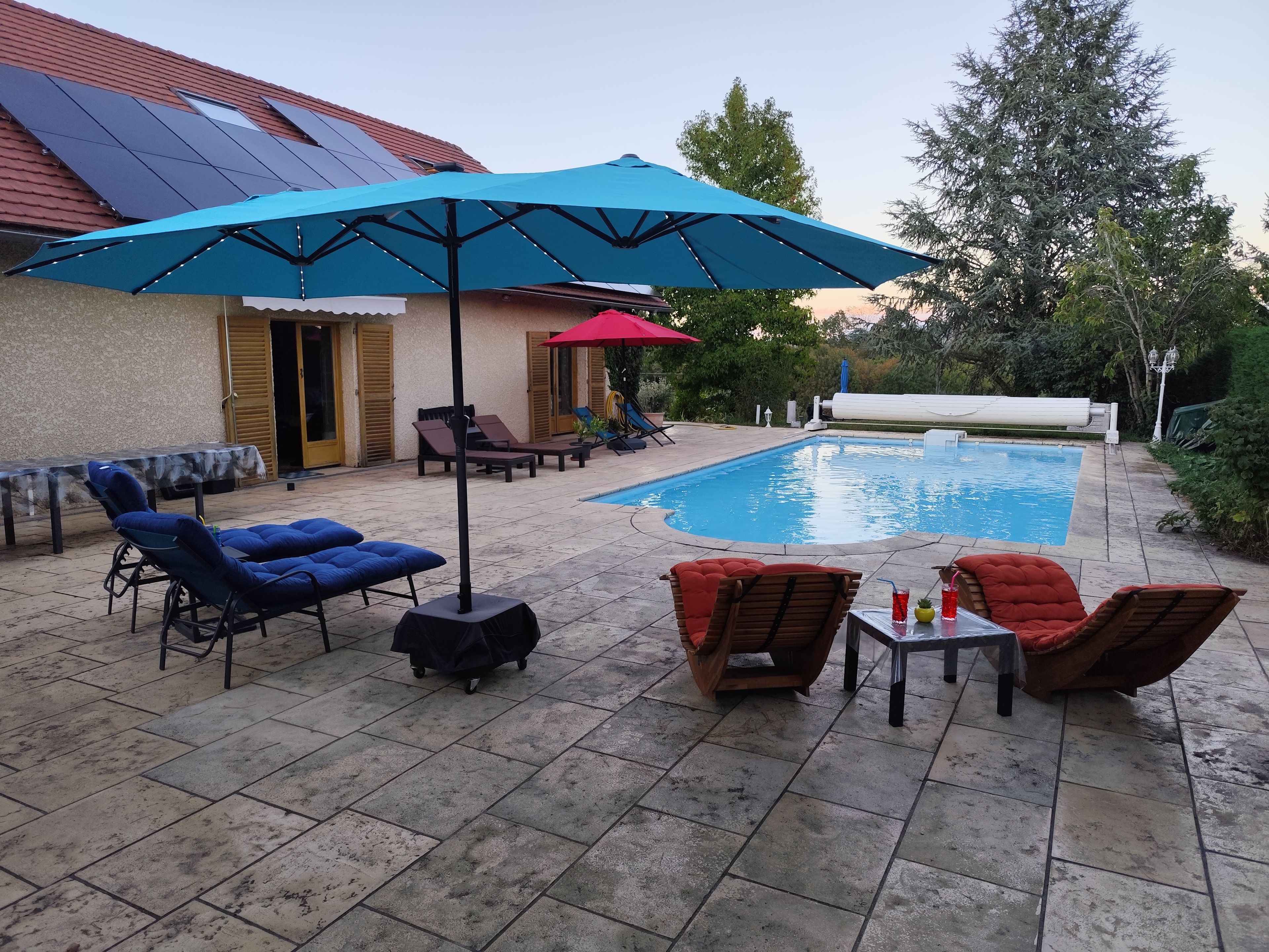 A swimming pool area with lounge chairs and umbrellas.