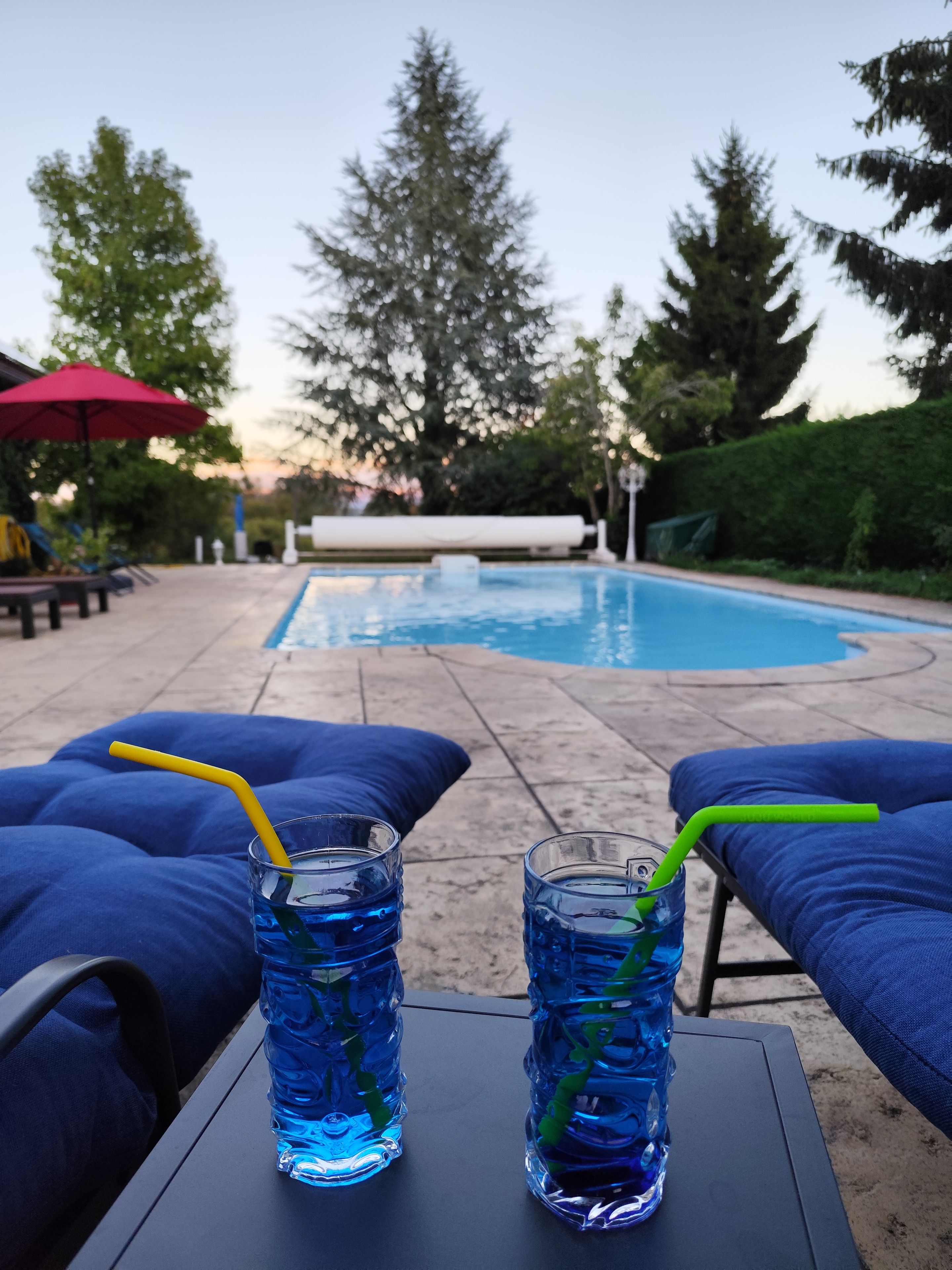 Ein Poolbereich mit Liegestühlen und zwei Gläsern blaues Getränk mit Trinkhalmen.