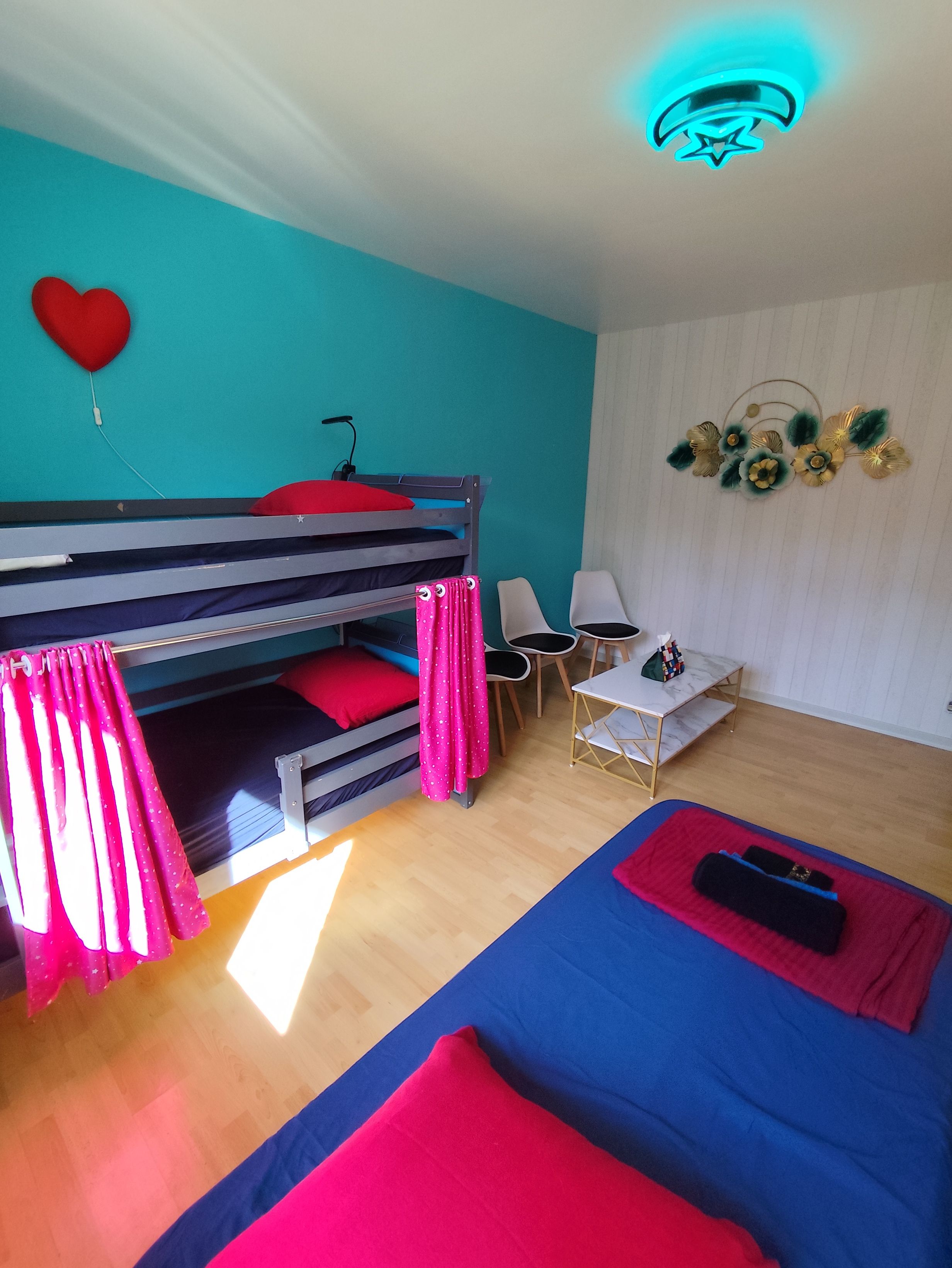 Ein Zimmer mit Etagenbetten, einem Schreibtisch, Stühlen und einer Wanddekoration.