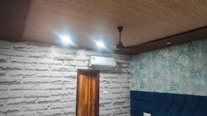 A room with a stone-textured wall, a wooden door, and a patterned wall. - Hotel O la casa (Amritsar)