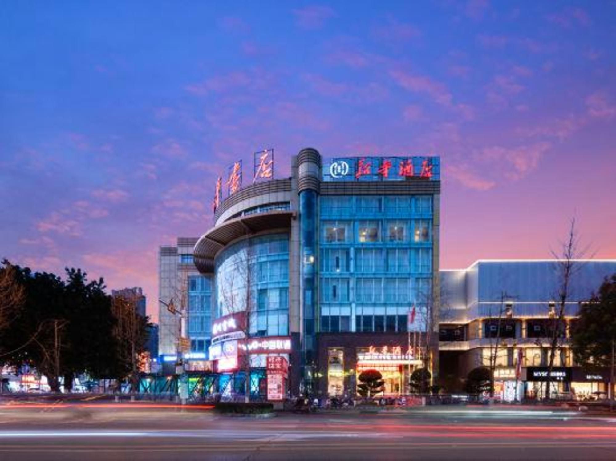 A modern hotel with a curved facade, multiple floors, and illuminated signage.