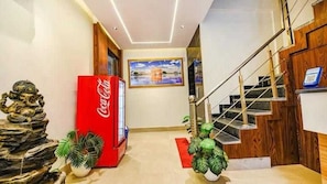 A modern interior with a staircase, a Coca-Cola refrigerator, and a painting on the wall. - Hotel O euro 98 (Amritsar)