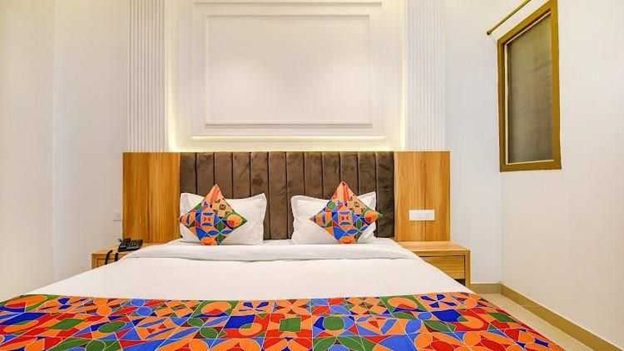 A hotel room with a bed, a nightstand, and a wall-mounted TV.