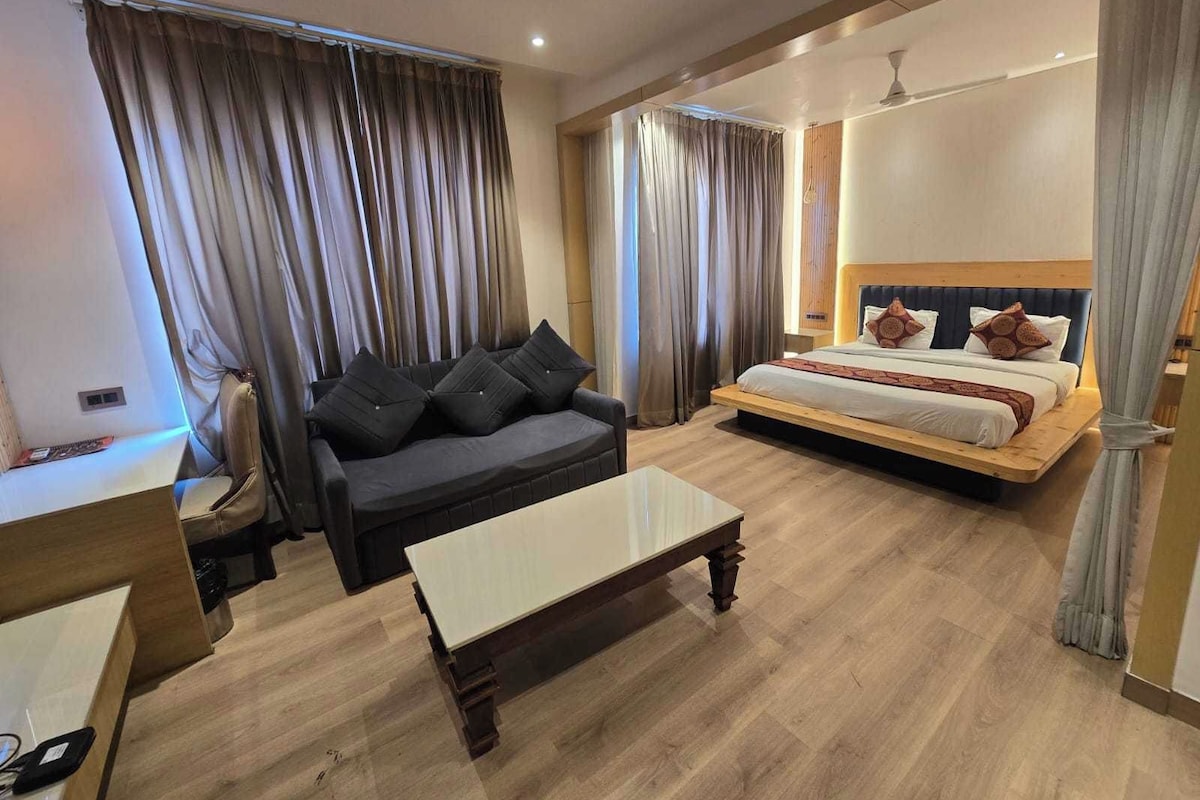 Habitació d'hotel amb llit, sofà, taula petita i mirall.