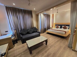 Habitació d'hotel amb llit, sofà, taula petita i mirall.