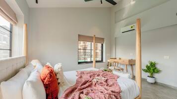 A bedroom with a bed, a bedside table, a mirror, a window, and a ceiling fan.
