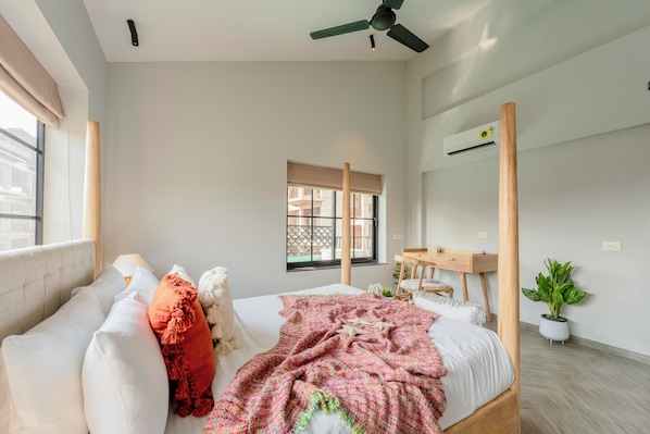 A bedroom with a bed, a bedside table, a mirror, a window, and a ceiling fan.