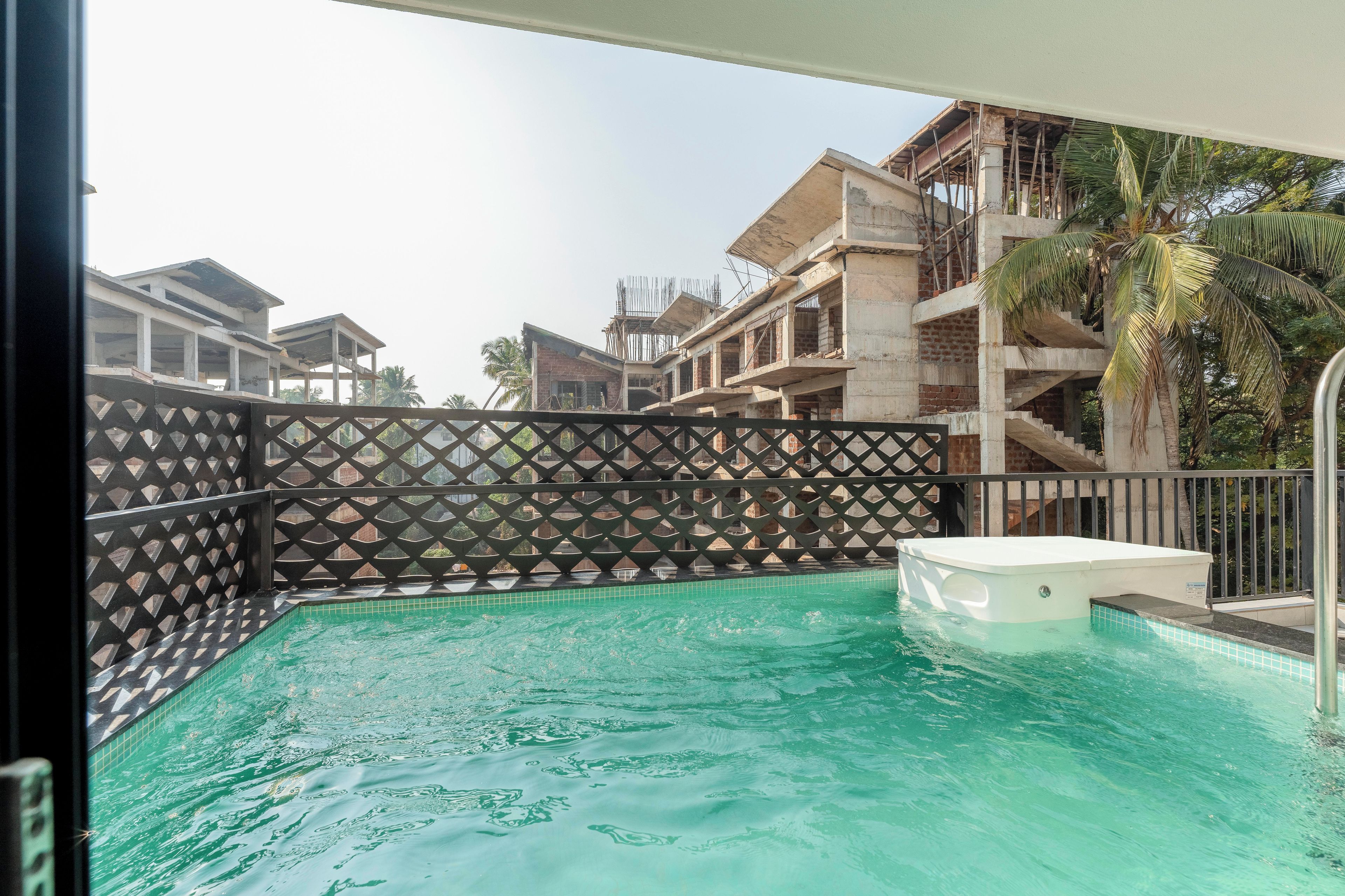 A swimming pool with a hot tub, surrounded by a fence with a geometric pattern.