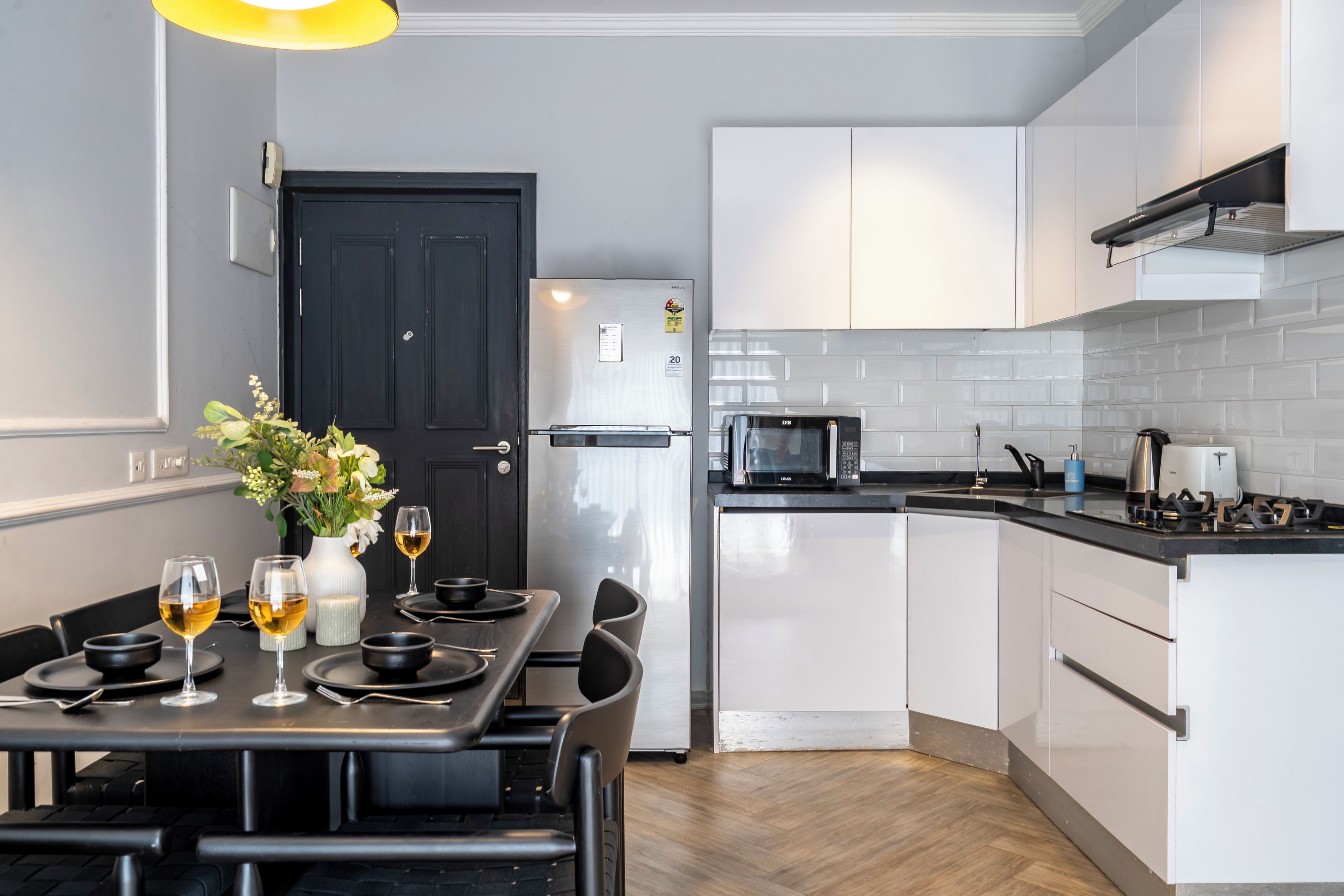 Una cocina moderna con armarios blancos, un refrigerador negro, un microondas y una estufa a gas.