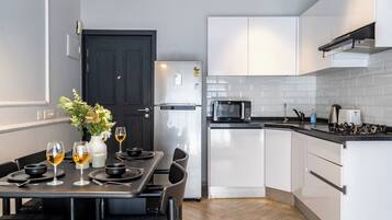 Una cocina moderna con armarios blancos, un refrigerador negro, un microondas y una estufa a gas.
