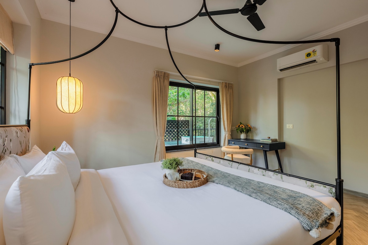 A hotel room with a bed, a desk, a window with curtains, and a ceiling fan.