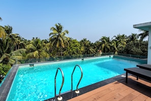A swimming pool with clear blue water, surrounded by lush greenery and palm trees.