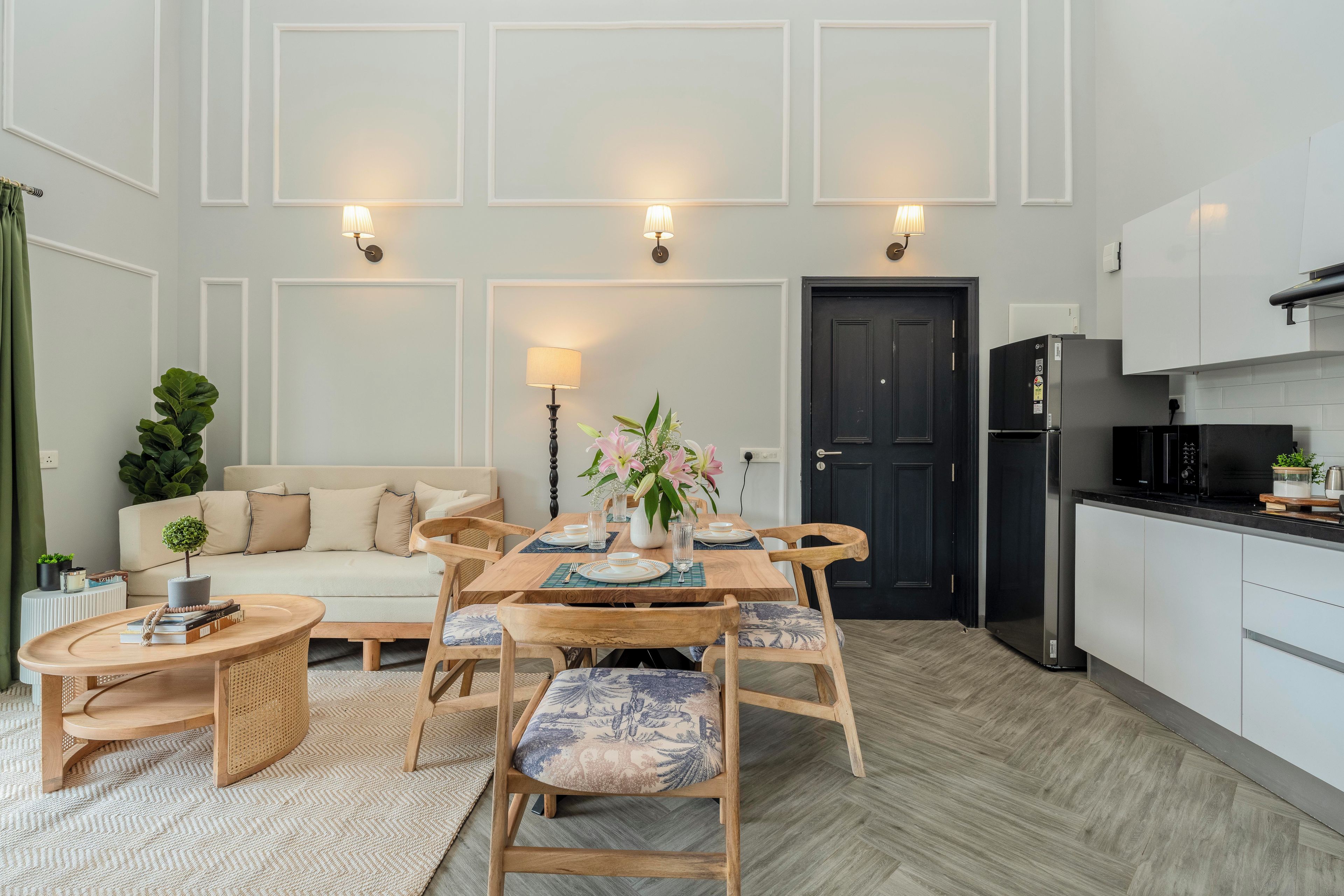 A modern kitchen with a dining area, a sofa, and a small side table with a plant.