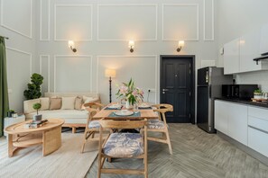 A modern kitchen with a dining area, a sofa, and a small side table with a plant.