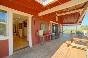 A covered outdoor deck with wooden flooring, a table, chairs, and a view of the landscape. - Spacious Beautiful Country Home on 8 Private Acres (Kelseyville)