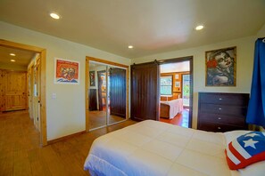 Une chambre à coucher comprenant un lit, une commode et une porte donnant sur une autre pièce.