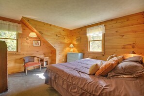 Habitació acollidora amb un llit, un escriptori i una cadira. Hi ha dues finestres amb cortines, una làmpada i un quadre a la paret.