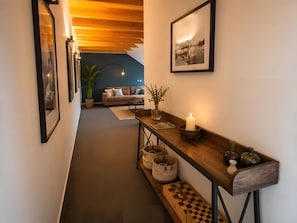 Ein Flur mit einer Holzbank, einer brennenden Kerze und einem gerahmten Bild an der Wand.