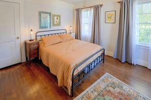 Ein Schlafzimmer mit einem Bett, Nachttischen, einem Teppich und Vorhängen.