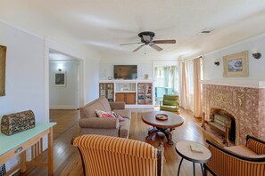 Ein Wohnzimmer mit einer Couch, Sesseln, einem Couchtisch, einem Kamin und einem Fernseher.