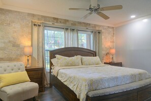 A bedroom with a bed, a nightstand, a chair, a window with curtains, and a ceiling fan. - Near ZooTampa & Buccaneers Games! Modern Retreat (Tampa)