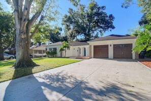 A residential house with a driveway, garage, and a large tree in the foreground. - Near ZooTampa & Buccaneers Games! Modern Retreat (Tampa)