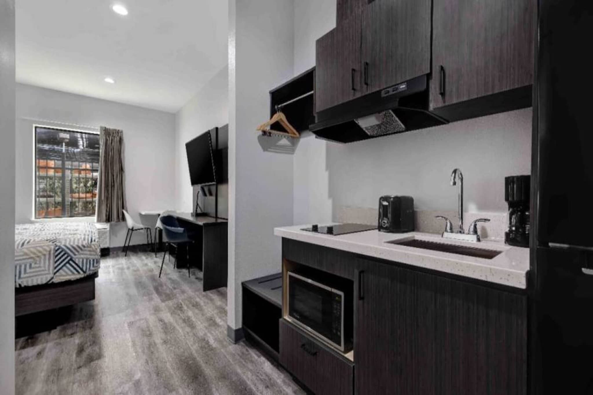 A modern kitchen with dark cabinetry, a built-in microwave, and a coffee maker.