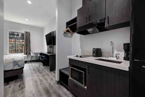 A modern kitchen with dark cabinetry, a built-in microwave, and a coffee maker. - 1 King Bed | Non-Smoking, Kitchen (Katy)