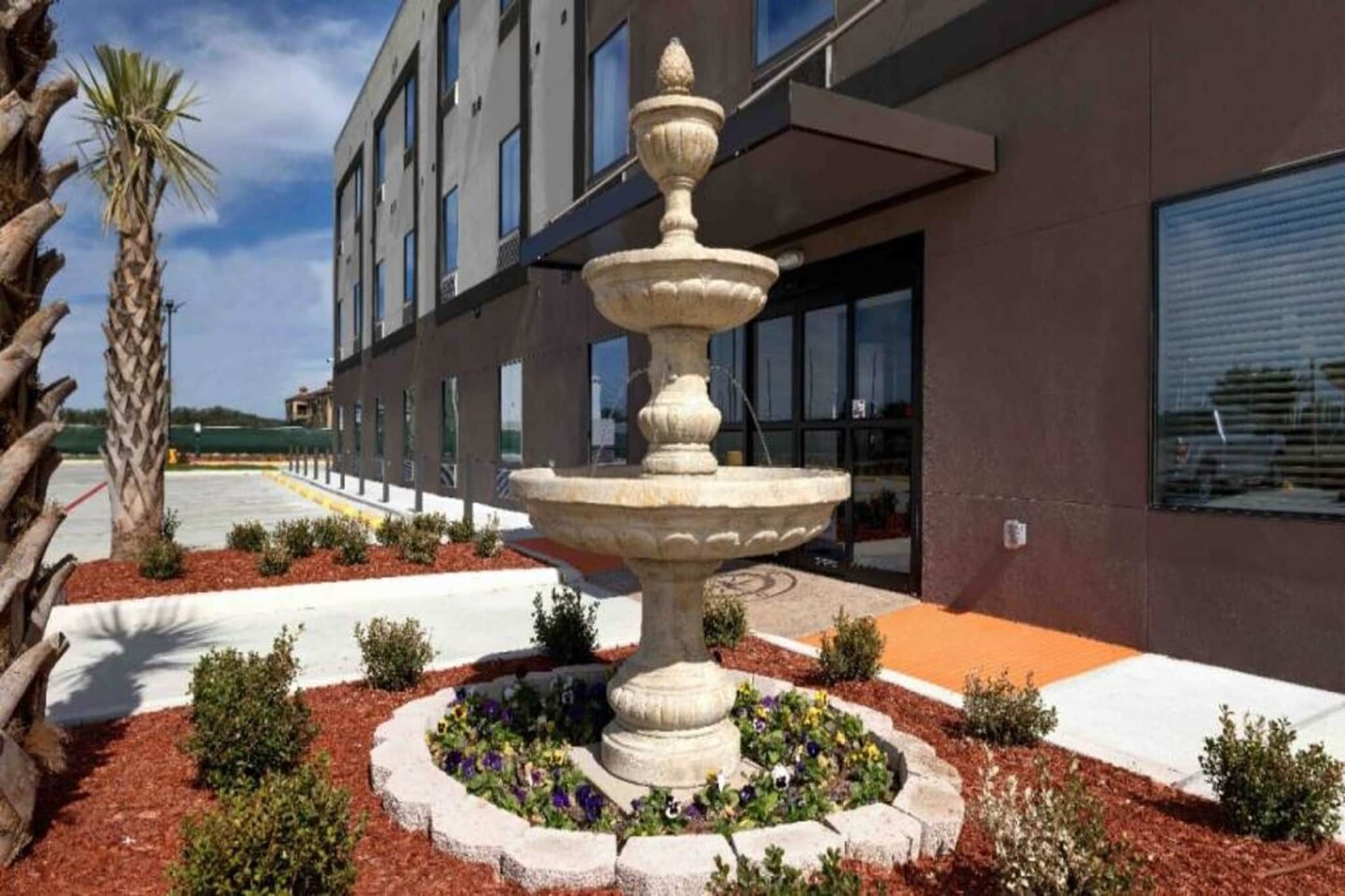 A modern building with a central fountain surrounded by landscaped garden beds.