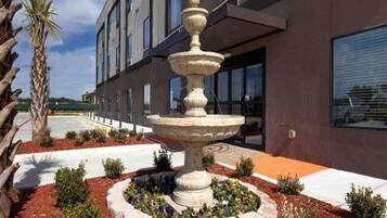 Un edificio moderno con una fuente central rodeada de jardines ajardinados.