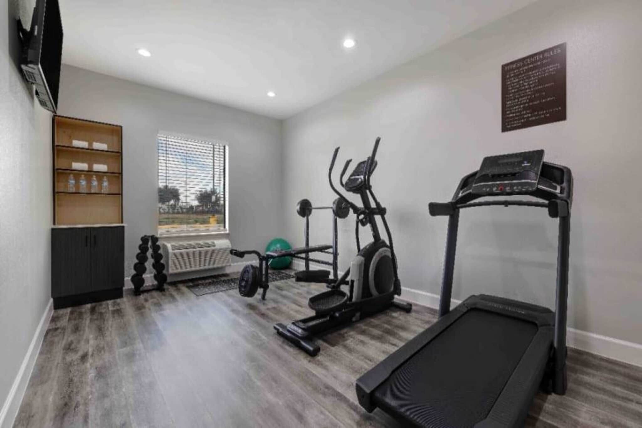 Un gimnasio en casa con cinta de correr, elíptica y pesas.