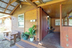 Una baita in legno con un portico, una panchina e piante in vaso.