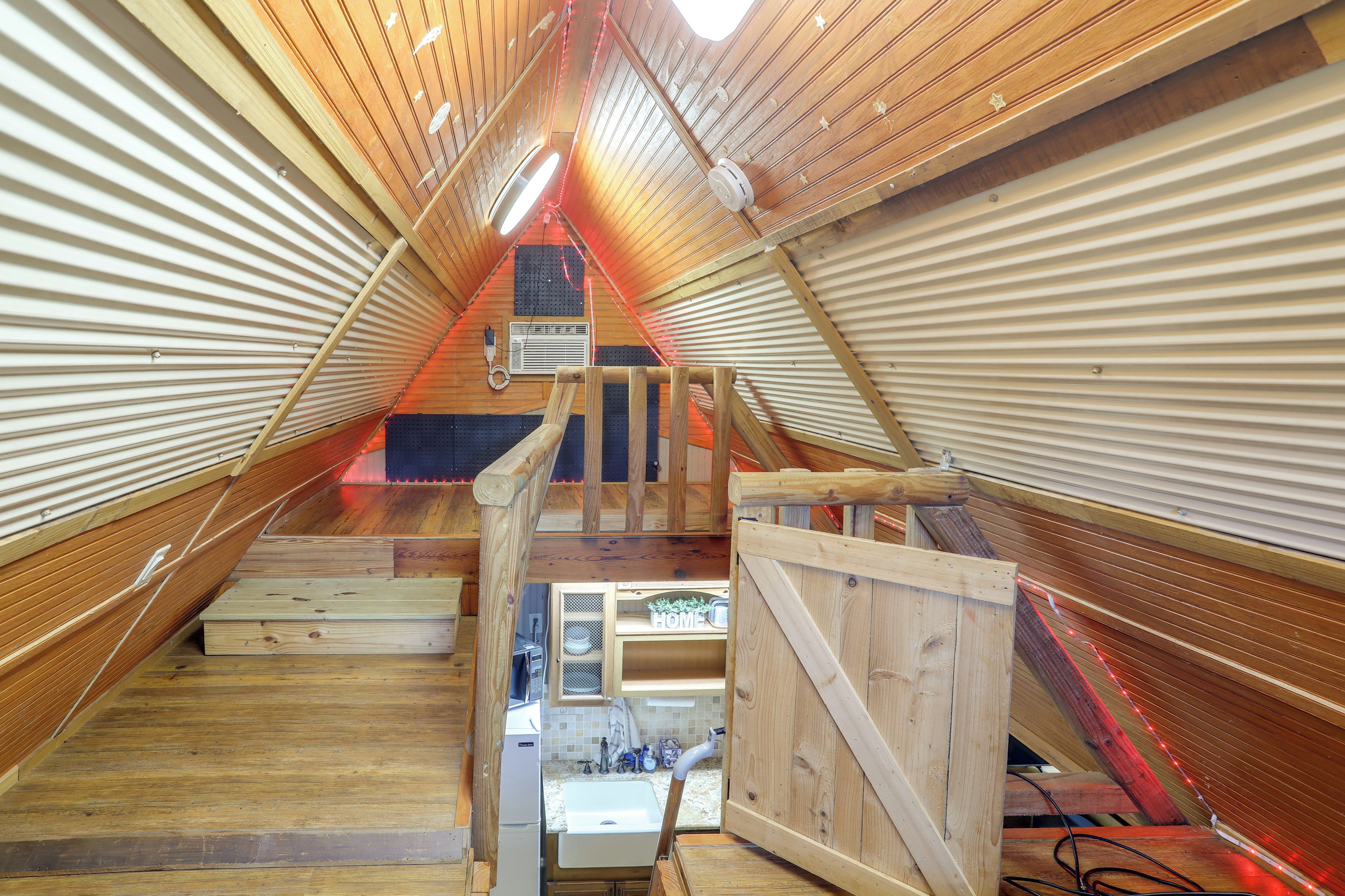 An attic bedroom with a wooden sloped ceiling, a small window, and a built-in heater.