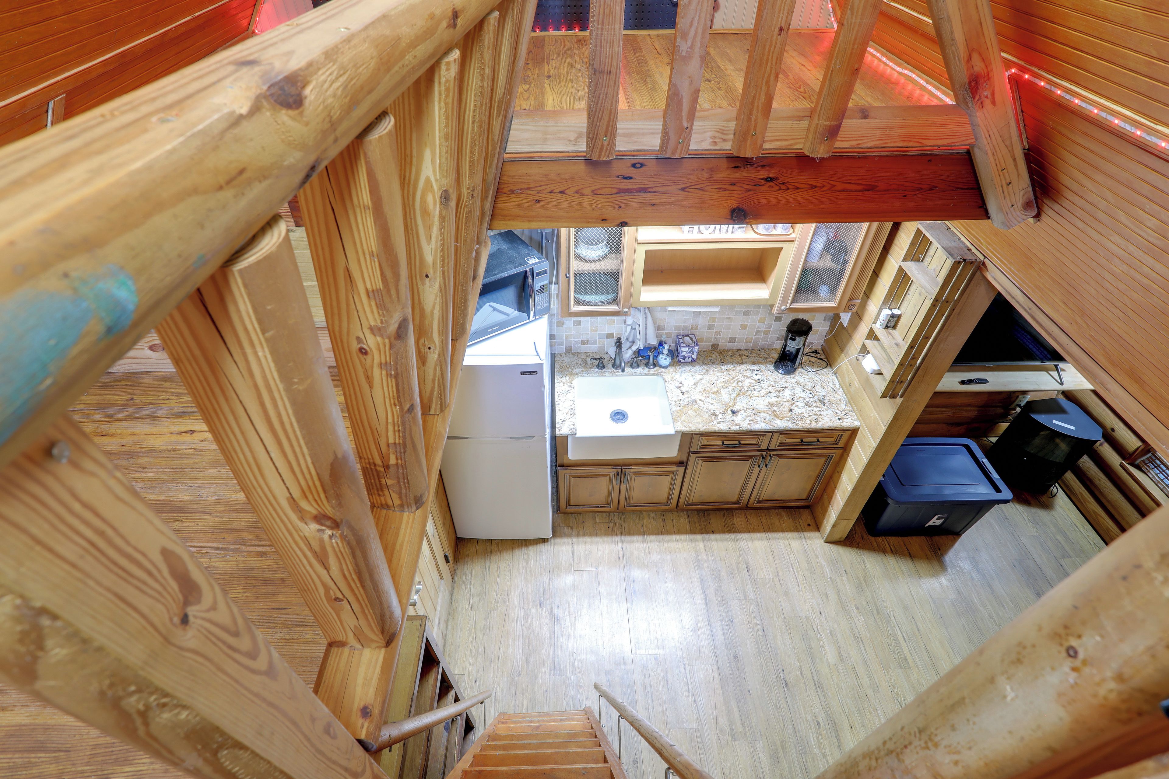 Une cuisine de taille réduite, équipée d’un réfrigérateur, d’un évier et de meubles de rangement en bois.