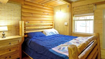 Camera da letto in baita con un letto, una cassettiera e una finestra.