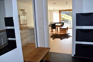Ein modernes Interieur mit einer Holzbank, einem Essbereich und Blick auf einen Hügel.