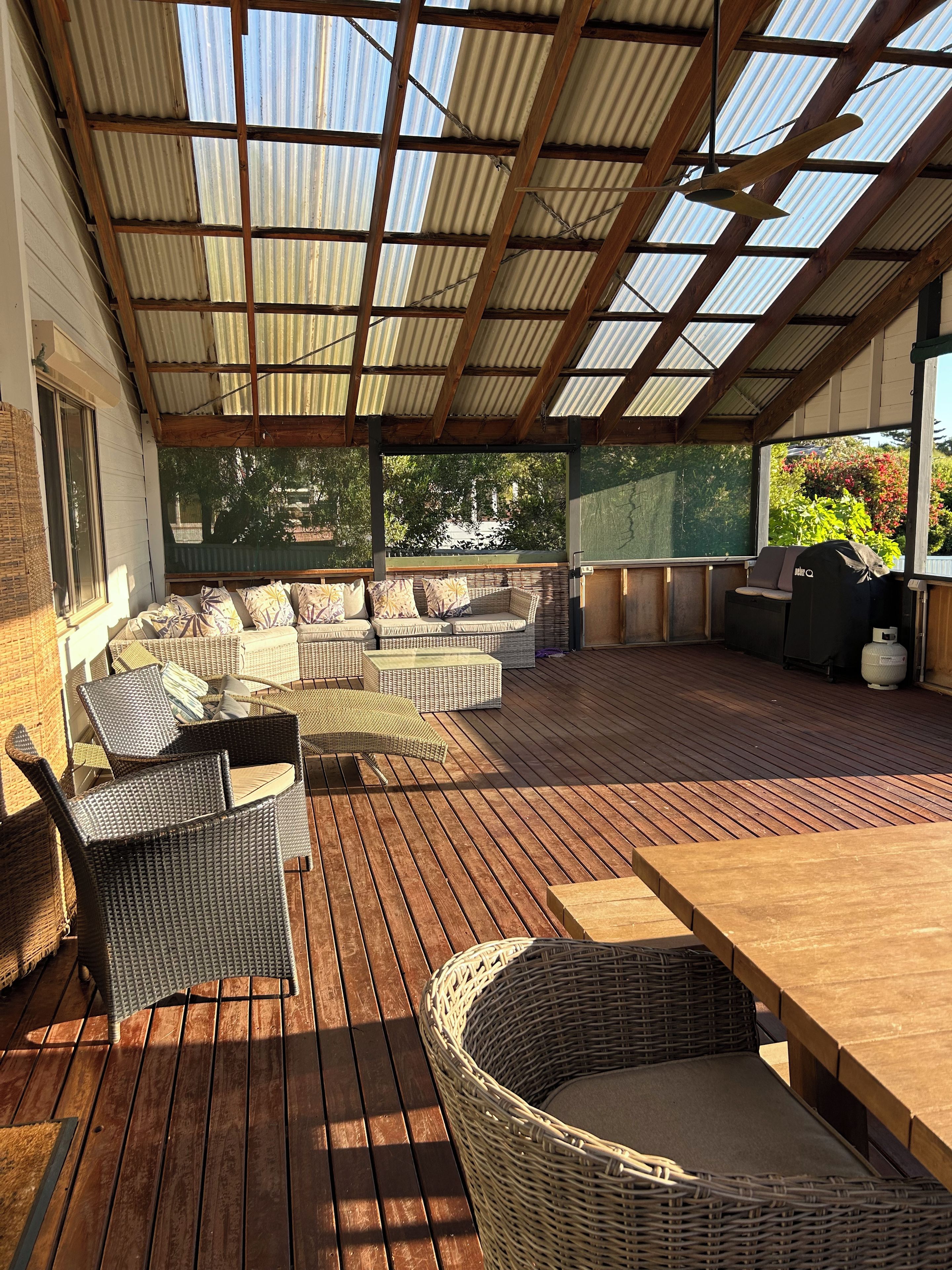 A covered outdoor patio with wicker furniture and a wooden table.