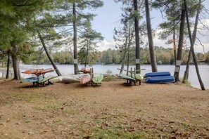 A lakeside area with several kayaks and canoes parked under trees. - Lakefront Escape in Eagle River! Boat, Fish + Play (Eagle River)