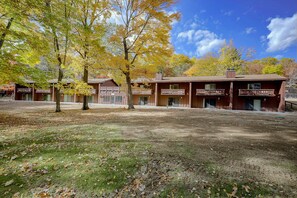 A building with multiple rooms, a covered outdoor area, and a lawn with fallen leaves. - Lakefront Escape in Eagle River! Boat, Fish + Play (Eagle River)