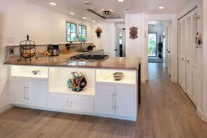 A modern kitchen with a large island, built-in cabinets, and a view to the backyard. - Luxury Manhattan Beach Home in Parklike Gated Community (Manhattan Beach)