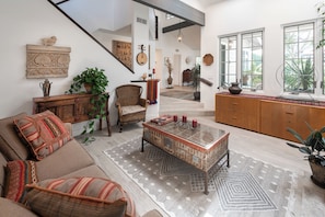 A spacious living room with a high ceiling, a staircase, and a view of the outdoors through large windows. - Luxury Manhattan Beach Home in Parklike Gated Community (Manhattan Beach)